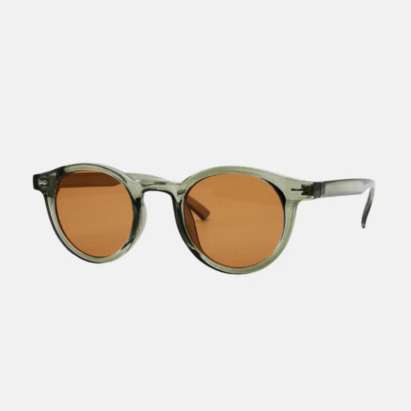Sunglasses Vero Green – Side-angled view of a round frame in a translucent green finish, paired with amber-tinted lenses. Keyhole bridge and slim temples with slightly curved ends for comfort. Subtle metallic accents near the hinges, displayed against a minimal light background. www.zenluk.com