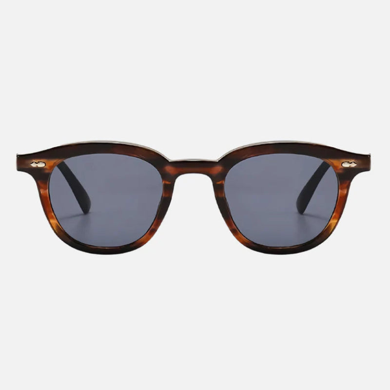 Sunglasses George Brown – Elegant unisex sunglasses featuring a rounded frame in a sophisticated tortoiseshell brown finish. The lenses are a deep gray with full UV protection, perfectly balancing style and functionality. The high-quality acetate frame has subtle silver rivet details on the front for a refined touch. A must-have accessory for any occasion. Discover more at www.zenluk.com