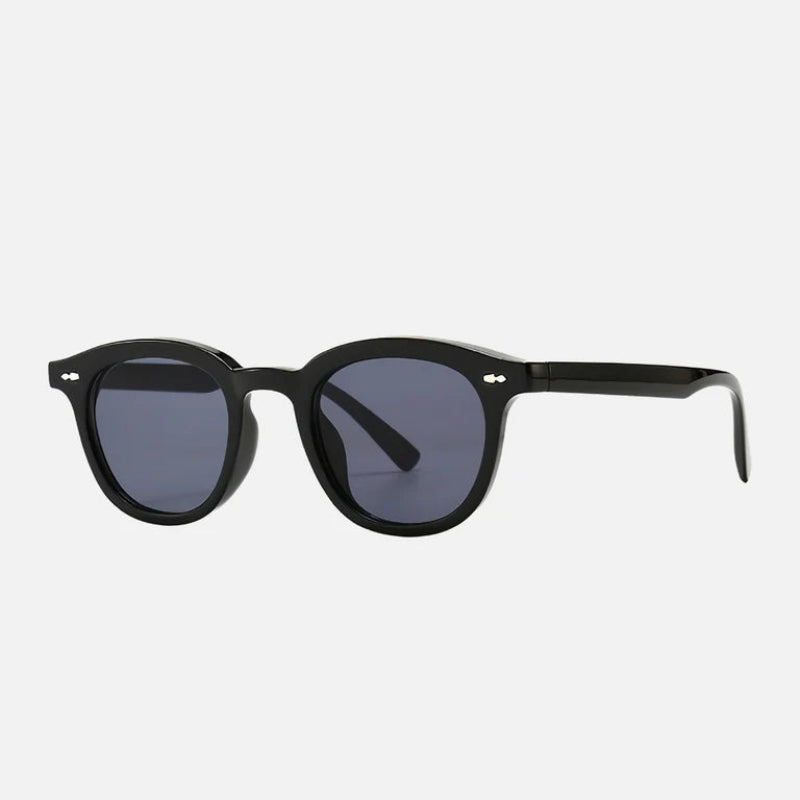 Sunglasses George in black, showcasing the side profile of its polished acetate frame. The round shape and dark blue lenses create a timeless aesthetic, while silver rivets add a refined detail to the temples. See the full collection at www.zenluk.com