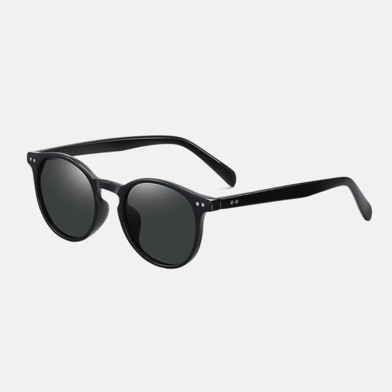 Sunglasses Lico Black – Elegant matte black round frame viewed from a side perspective, showcasing the smooth curvature of the temples and the minimalist design. Double silver rivets are visible on the front and sides, paired with deep black lenses for a timeless, modern look. www.zenluk.com