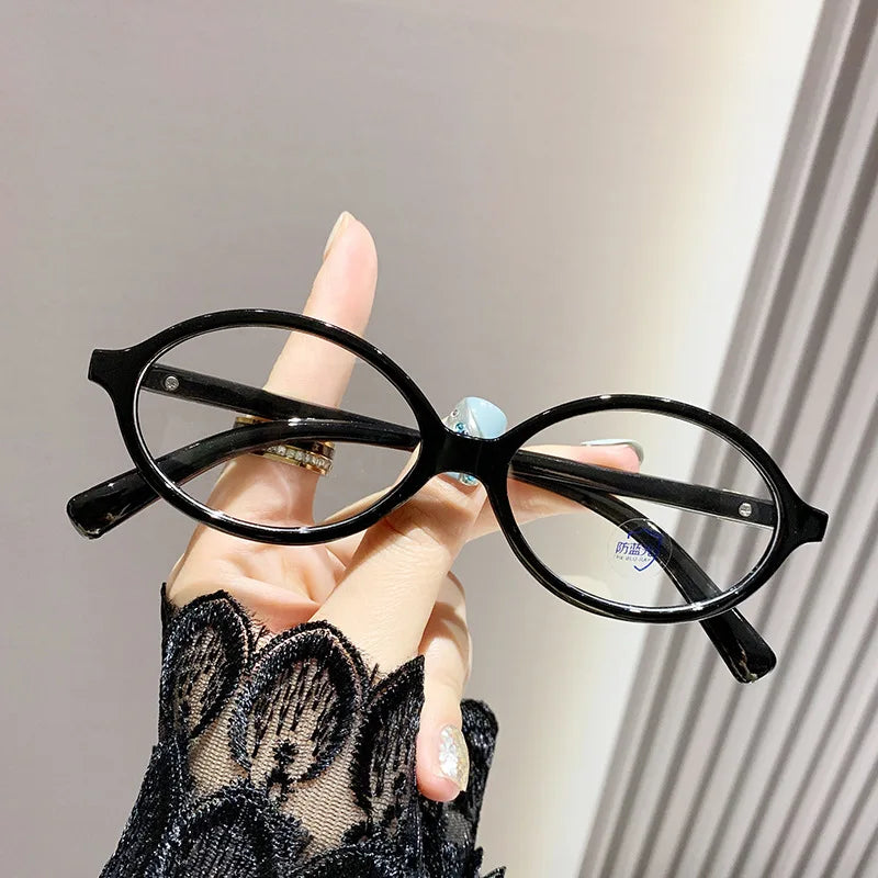 Woman Holding Blue Light Glasses Shine with Black tortoiseshell frame, oval-shaped design and clear blue light filter lenses. Lightweight and stylish, these glasses reduce eye strain, improve sleep, and protect your eyes from harmful screen glare. Ideal for long hours in front of computers, phones, and tablets. Comfortable for everyday wear with a premium look and smooth fit. Available now at www.zenluk.com