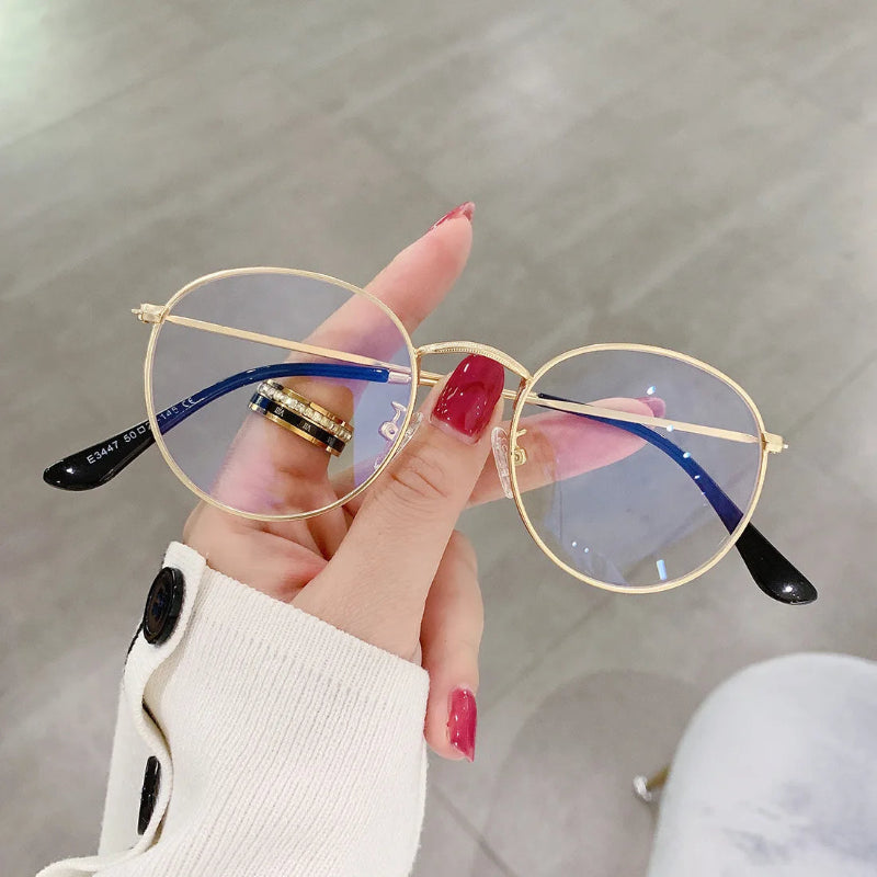 Woman Holding a Blue Light Glasses Milan Gold frame, elegant and lightweight round design. Reduces blue light exposure, eye strain and improves sleep. Ideal for extended screen use on laptops, tablets, and phones. Comfortable nose pads and durable metal finish. www.zenluk.com