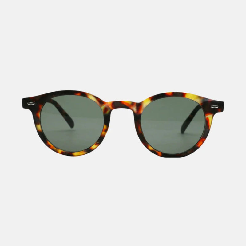 Sunglasses Vero Leopard Green – round frame in a glossy tortoiseshell pattern blending amber, brown, and black tones, featuring dark green polarized lenses and subtle metallic details on the temples, photographed on a light grey background – www.zenluk.com